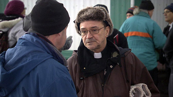 L'abbé Claude Paradis discutant avec une personne en situation d'itinérance