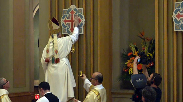 Archbishop Lépine, ointing one of the 12 crosses of consecration during the celebration.