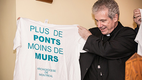 Mgr Christian Lépine qui tient un chandail "Plus de ponts moins de murs" lors du lancement officiel du Pont. (Photo : Le Pont)