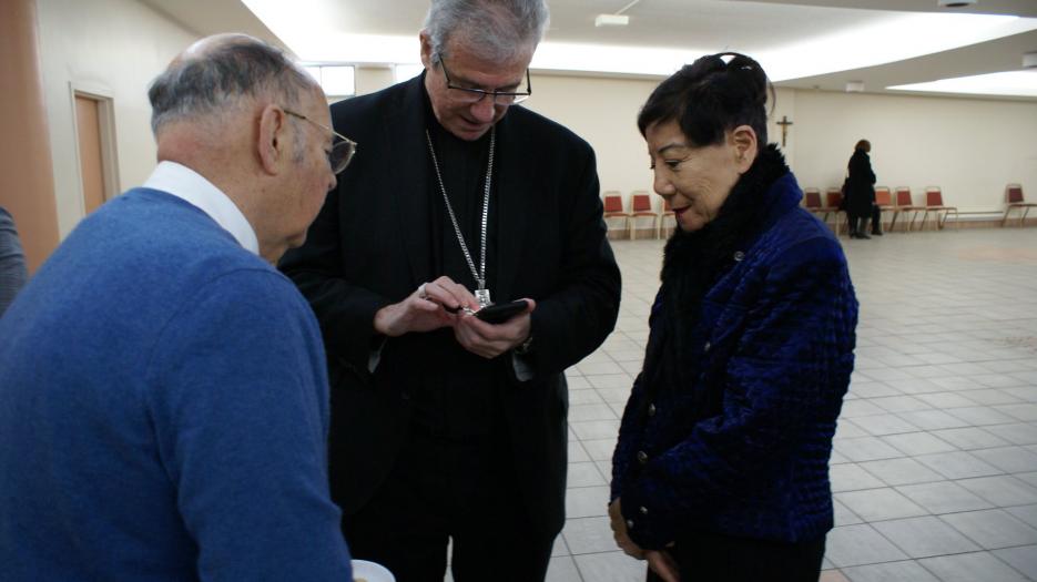 Mgr Lépine fait-il une démonstration de l'application mobile du diocèse? (Photo : Brigitte Bédard)
